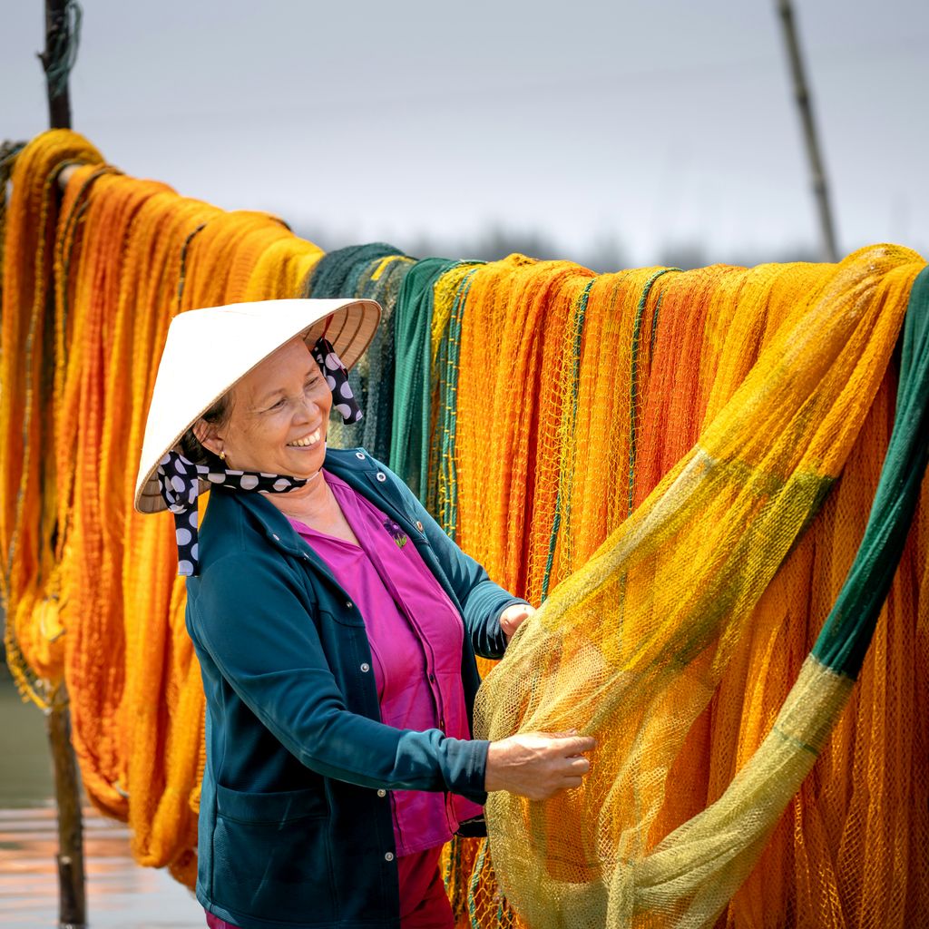 a woman standing next to a line of orange and yellow scarves