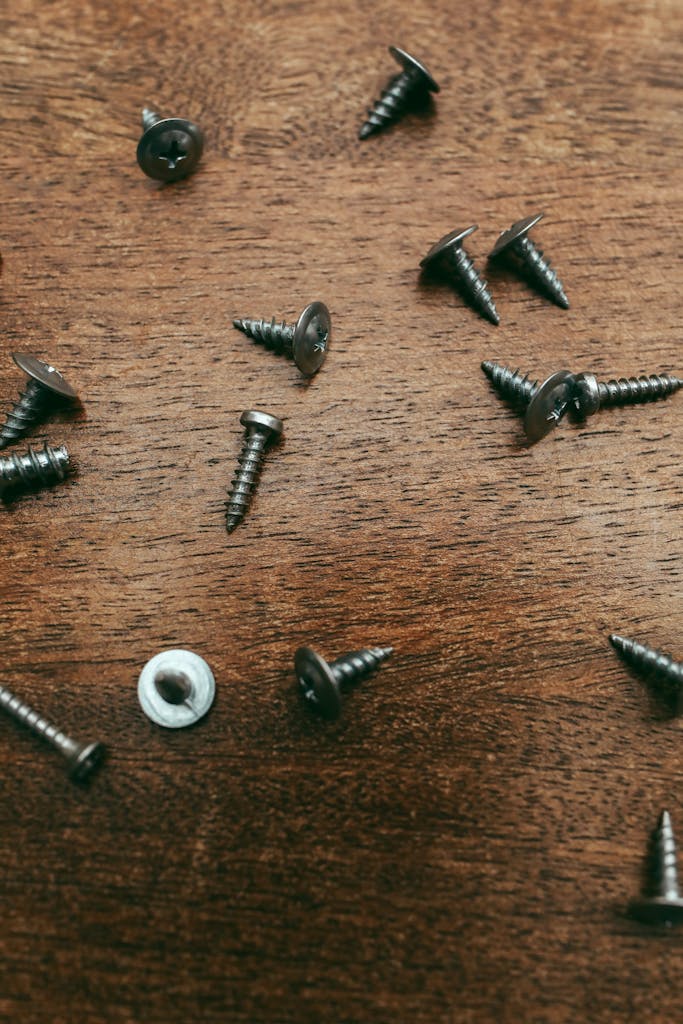 Detailed image of metal screws scattered on a wooden surface, ideal for carpentry-themed projects.
