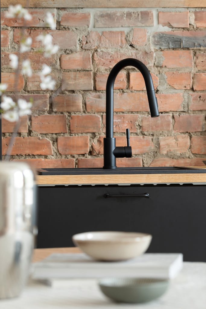 Stylish modern kitchen featuring black faucet, brick wall, and contemporary design elements.