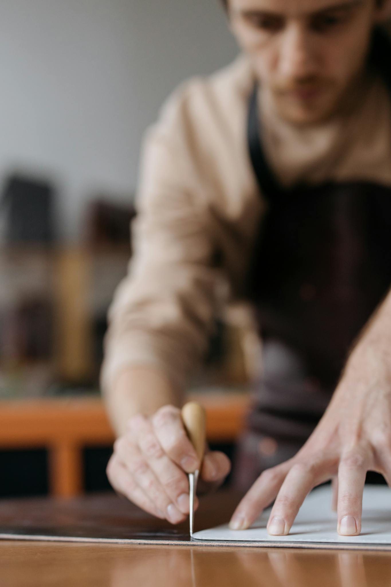 Close-up of a craftsman precisely marking wood with a chisel indoors, showcasing skilled hands and tools.