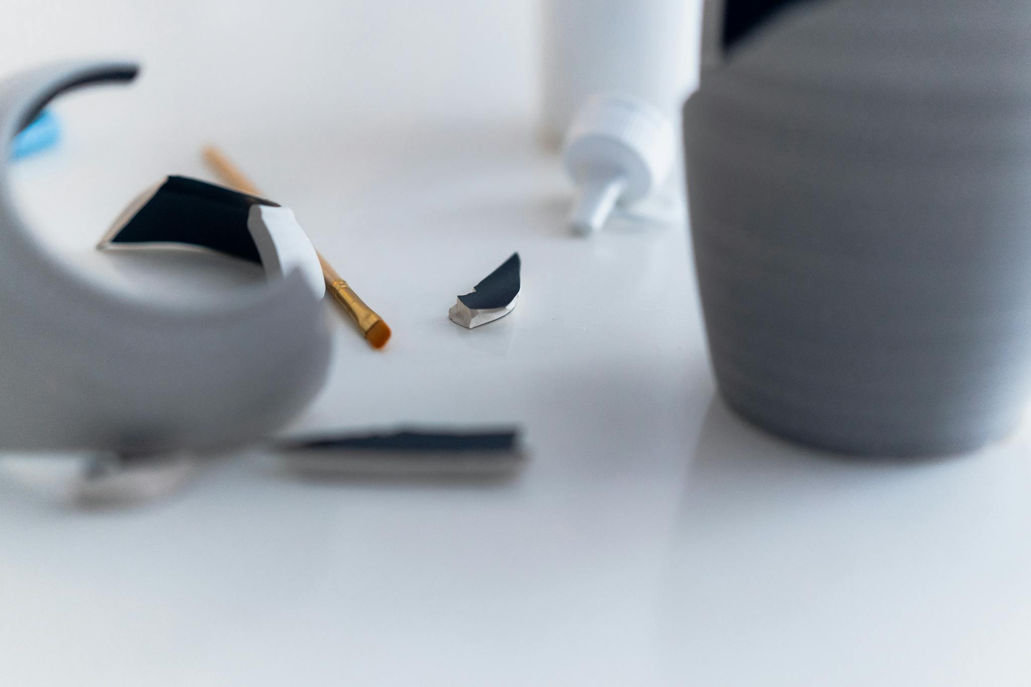 Close-up of a gray vase repair with glue and focus on broken pieces.