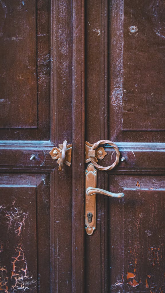 Close-up of a rustic wooden door featuring an antique handle and weathered texture.