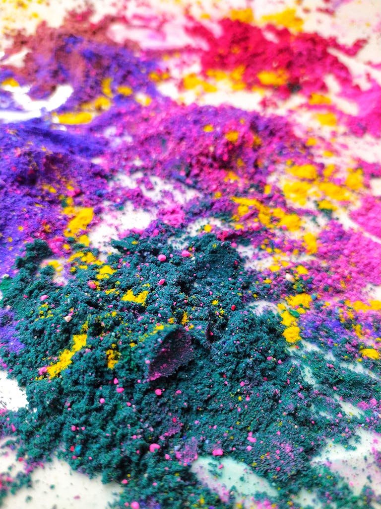 Close-up of vibrant colorful powders on a white surface, showcasing a striking mix of colors.